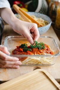 unrecognizable cook with container of pasta with bolognese sauce