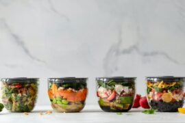 four clear plastic bowls with vegetables